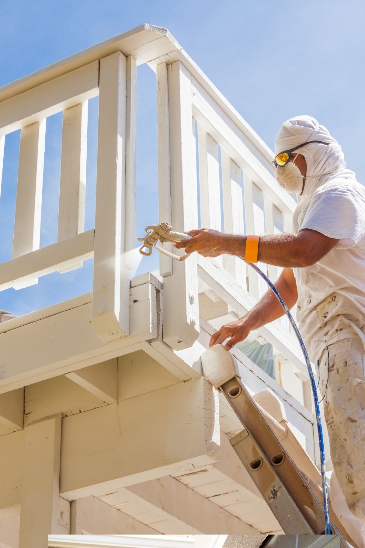 Peintre en bâtiment à La tuque appliquant une couche de peinture blanche